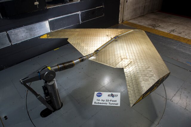 Wing assembly is seen under construction, assembled from hundreds of identical subunits, in a NASA wind tunnel